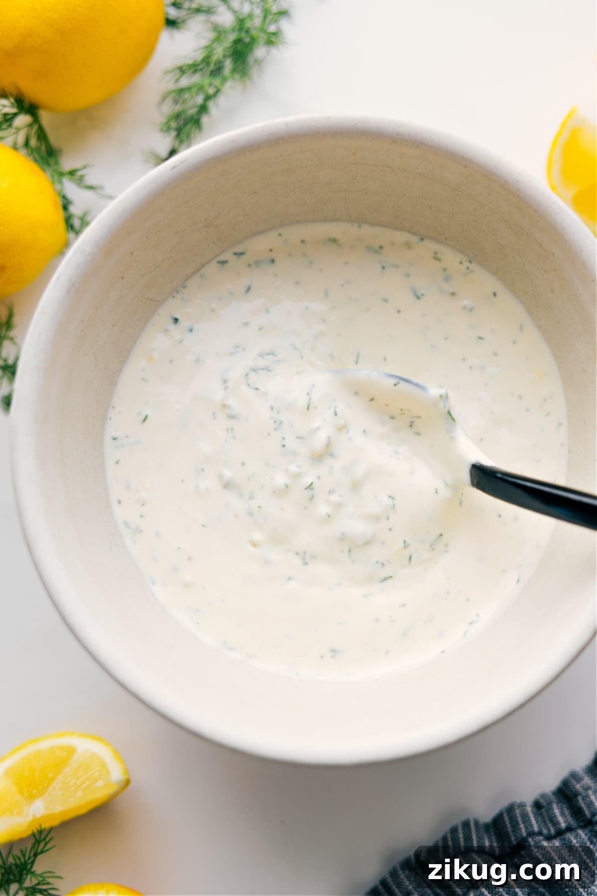 Homemade Tartar Sauce: The ultimate tangy and creamy condiment for elevating any seafood dish or savory snack. A beautifully presented bowl of creamy homemade tartar sauce, garnished with fresh dill, ready to serve alongside crispy fried fish and lemon wedges. The vibrant green of the dill contrasts with the rich white sauce.