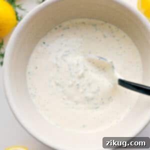 A vibrant and creamy bowl of homemade tartar sauce garnished with fresh dill, ready to be served.