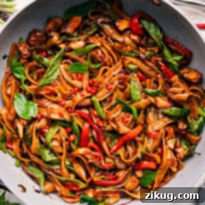 A delicious bowl of Thai Drunken Noodles, garnished with fresh basil.
