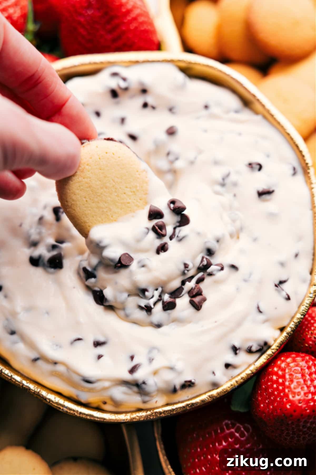 Indulgent And No-Bake Chocolate Chip Dip Close-up of creamy chocolate chip dip, generously topped with mini chocolate chips, with a cookie poised mid-dip, inviting indulgence.