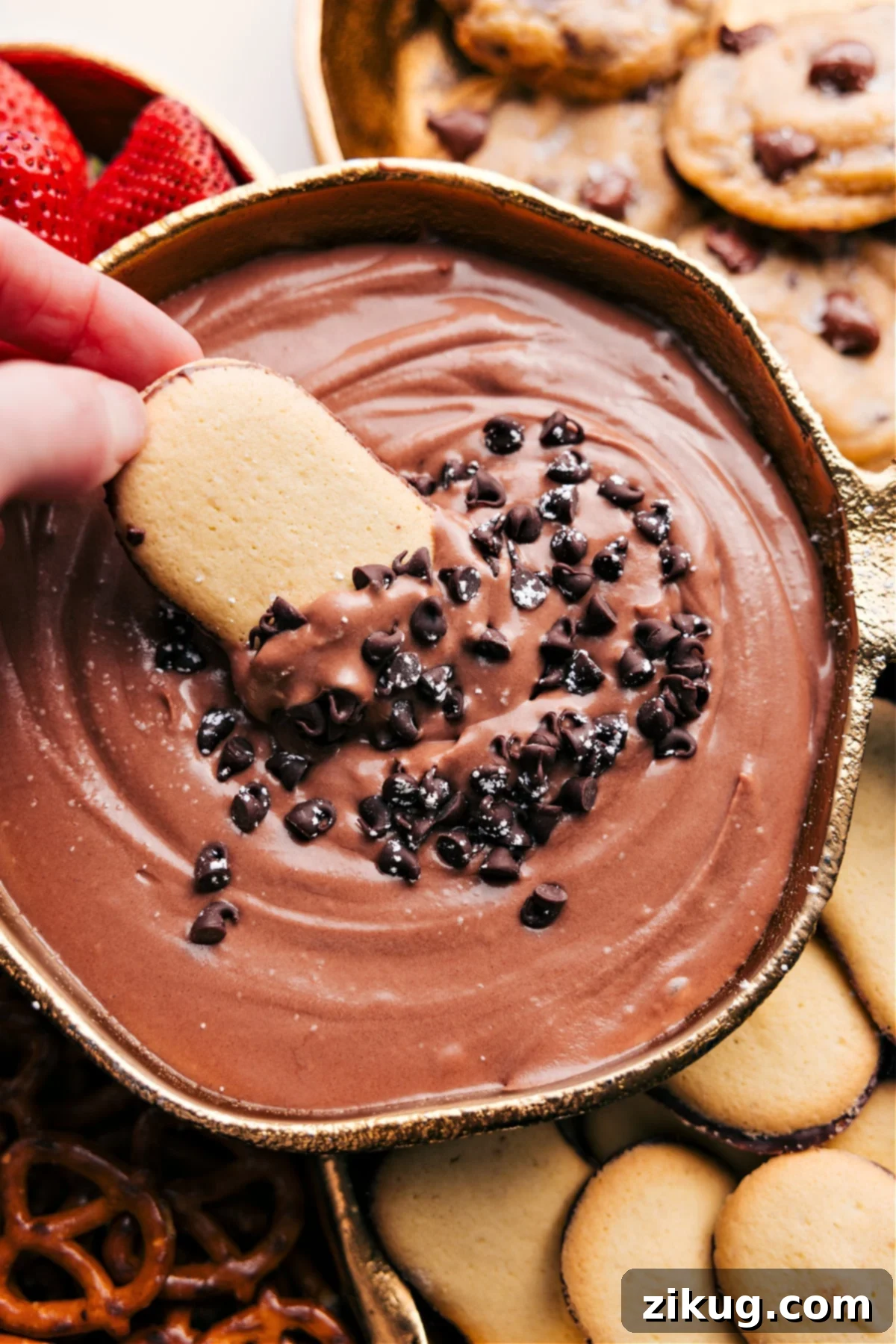 Chocolate Fruit Dip Is The Ultimate Dessert Rich chocolate fruit dip topped with chocolate chips, with a golden cookie being dipped into the creamy dessert.