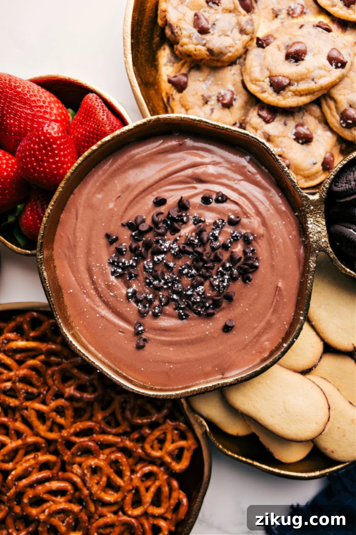 Dip Your Fruit In The Best, Most Decadent Dip The decadent chocolate fruit dip in a bowl surrounded by a variety of delicious dipping options like strawberries, cookies, and pretzels.