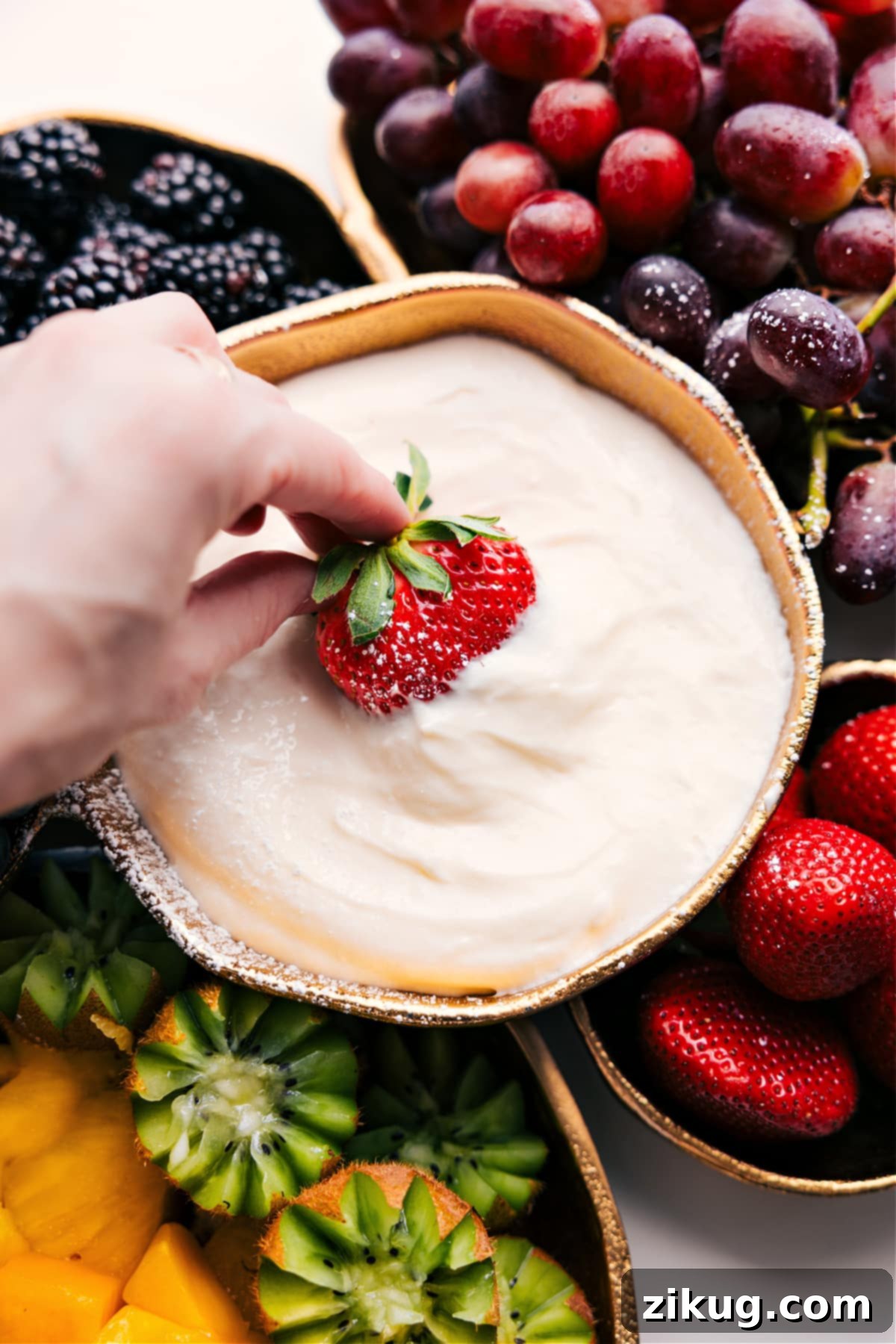 Simple, No-Bake Cream Cheese Fruit Dip Recipe Cream Cheese Fruit Dip Recipe with a vibrant strawberry being dipped in, showcasing its creamy texture.