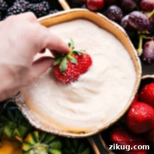 Finished Cream Cheese Fruit Dip served in a white bowl with fresh fruit surrounding it.