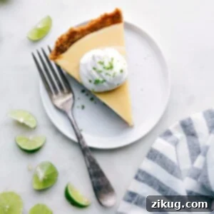 Slice of creamy key lime pie with a dollop of whipped cream on top, ready for serving.