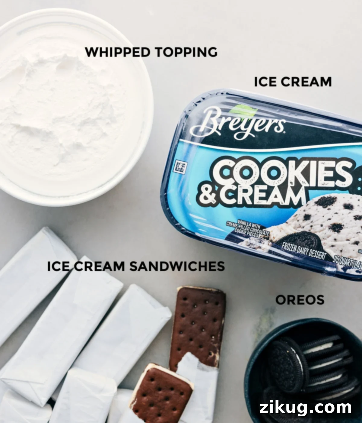 Simple Ingredients for Quick Ice Cream Sandwich Cake All four essential ingredients for the Ice Cream Sandwich Cake laid out neatly on a counter: a box of ice cream sandwiches, a container of cookies and cream ice cream, a tub of whipped topping, and a pack of Oreo cookies.