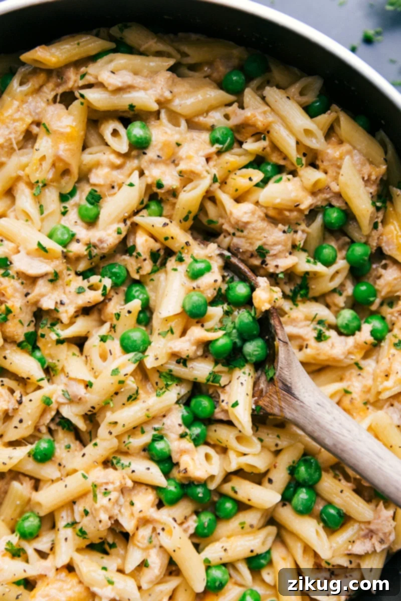 A comforting and cheesy Tuna Pasta dish with green peas, served in a skillet.