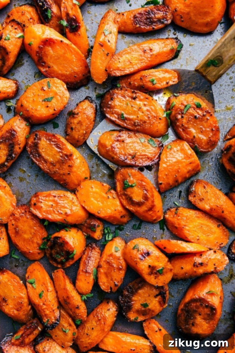 Sweet and savory Roasted Carrots on a baking tray, garnished with fresh herbs, ready for a simple spring side.