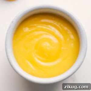 A jar of homemade lemon curd with fresh lemon slices.