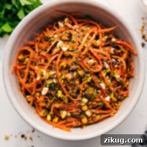 The final Ribbon Carrot Salad, garnished with fresh herbs and pistachios, presented in a rustic serving bowl.