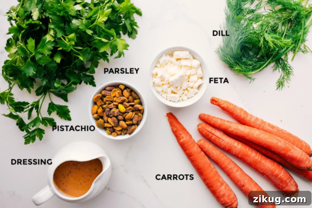 A collection of fresh ingredients for the Ribbon Carrot Salad, neatly arranged on a counter: peeled julienned carrots, fresh dill, parsley, shelled pistachios, feta cheese, and a jar of homemade lemon-Dijon dressing.