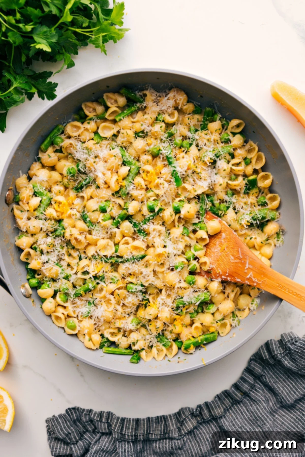 One Pot Asparagus Pasta Recipe Asparagus pasta recipe in a pot topped with freshly grated Parmesan cheese, with a spoon ready to serve.