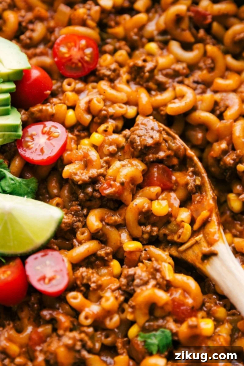 Taco Pasta Ready in 30 Minutes or Less A spoon scooping up cheesy Taco Pasta, showcasing visible melted cheese, perfectly seasoned meat, and tender pasta.