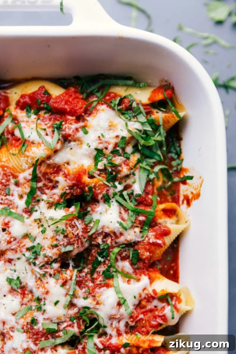 Quick & Easy Stuffed Shells with Sausage A pan of delicious, extra-cheesy Stuffed Shells with Sausage, topped with melted golden cheese and fresh basil chiffonade, offering a warm and satisfying meal for any occasion.