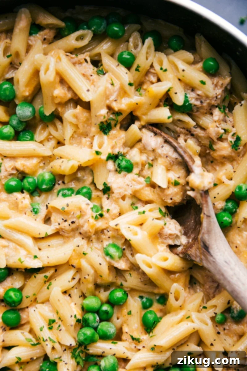 Quick 30-Minute Tuna Pasta Delight The finished one-skillet Tuna Pasta recipe with peas, featuring a spoon scooping up a cheesy and comforting portion.