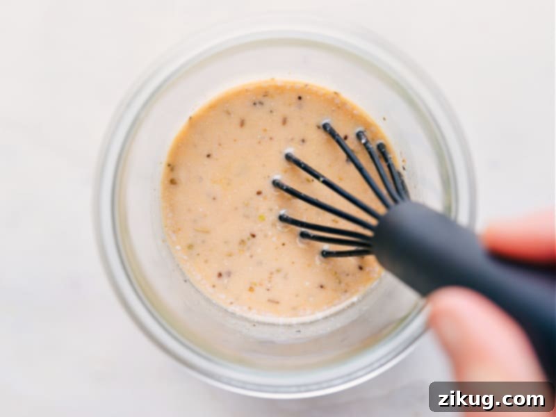 Crafting the perfect Italian Dressing with a rich texture and exquisite flavor is simpler than you think. Overhead shot of freshly prepared Italian Dressing being whisked in a bowl, showing its vibrant color and smooth texture