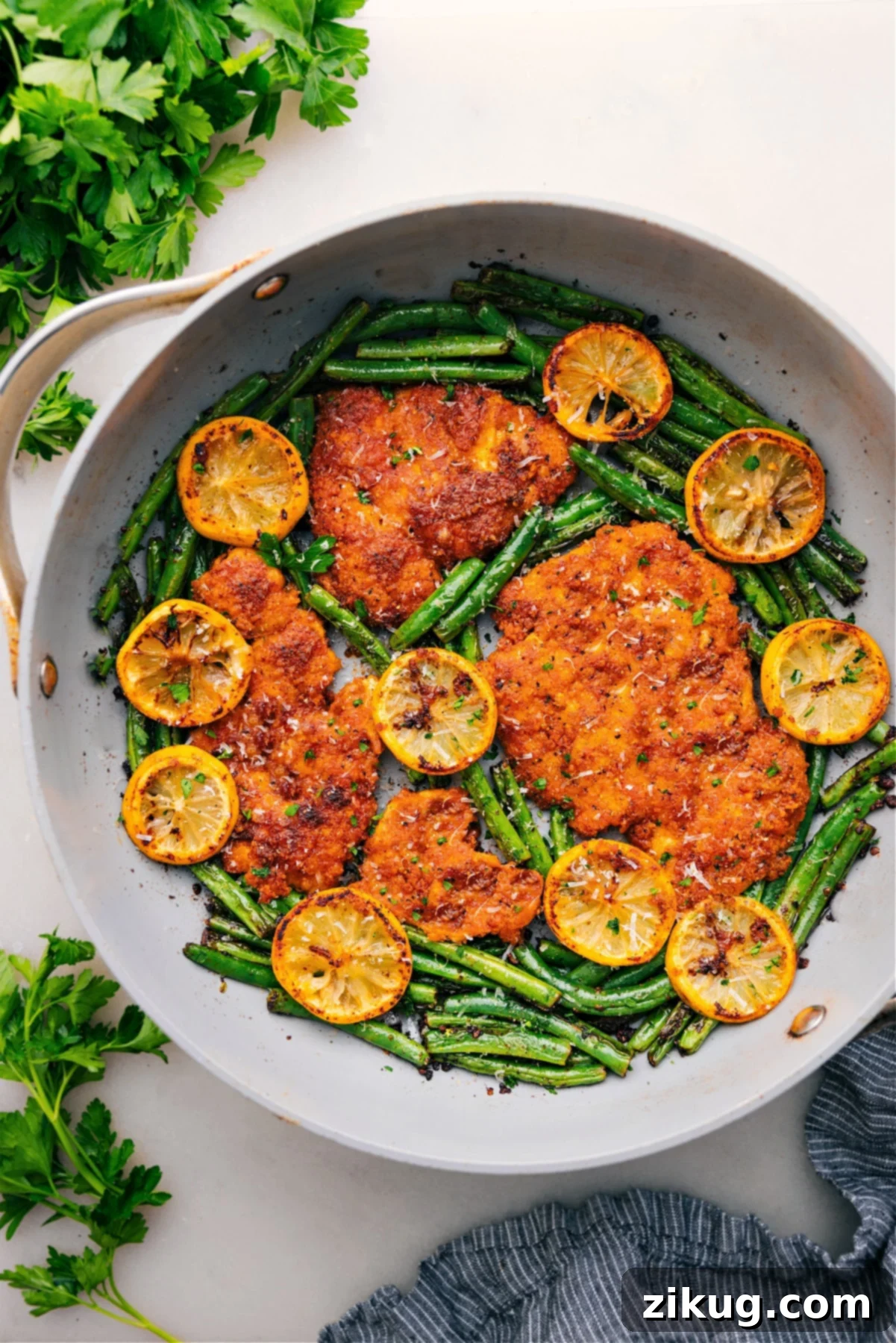 Savory One Pan Lemon Parmesan Chicken One-pan lemon parmesan chicken with charred green beans and a glistening lemon butter sauce, offering a bright and savory complete meal.