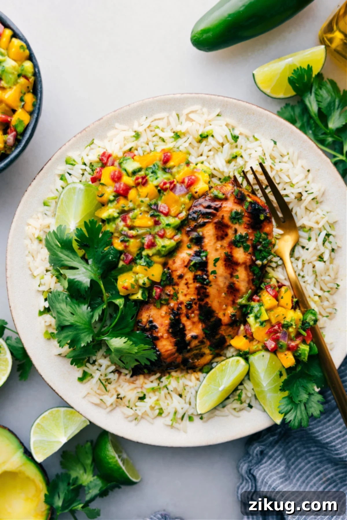 Zesty Cilantro Lime Chicken with Salsa A vibrant Cilantro Lime Chicken served over a bed of rice, garnished with fresh mango avocado salsa, creating a refreshing and flavorful meal.