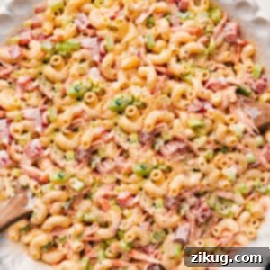 A serving of the best creamy Macaroni Salad, featuring tender elbow pasta and fresh vegetables coated in a rich, flavorful dressing, garnished with fresh parsley.