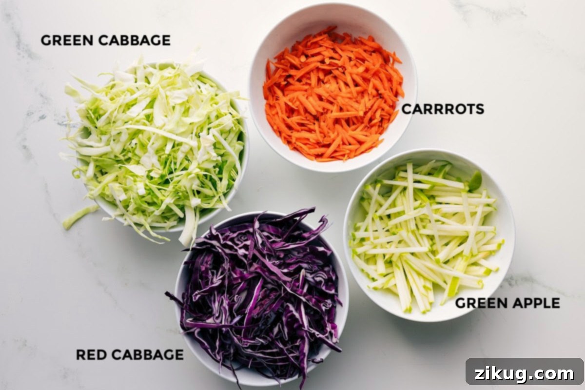 Easy Coleslaw Recipe Ingredients All the fresh ingredients for this Easy Coleslaw Recipe laid out and prepped for assembly, including thinly sliced green and red cabbage, grated carrots, and crisp green apple matchsticks.