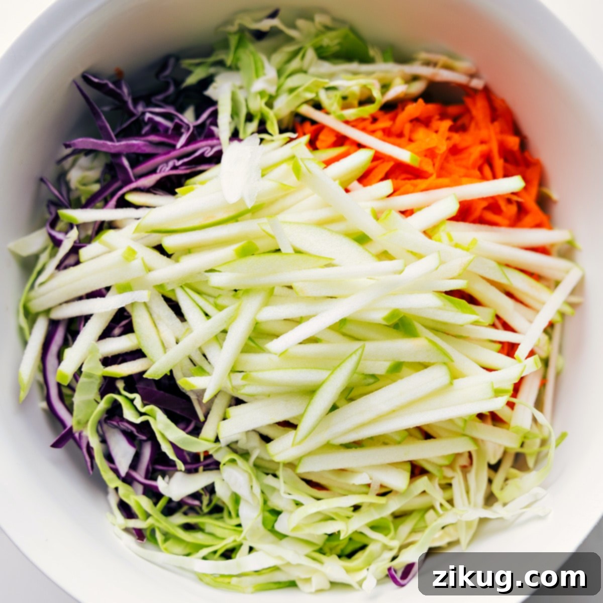 Assembling The Easy Coleslaw Recipe Base ingredients for the Easy Coleslaw Recipe, including green and red cabbage, and shredded carrots, added to a large mixing bowl, ready for the dressing.