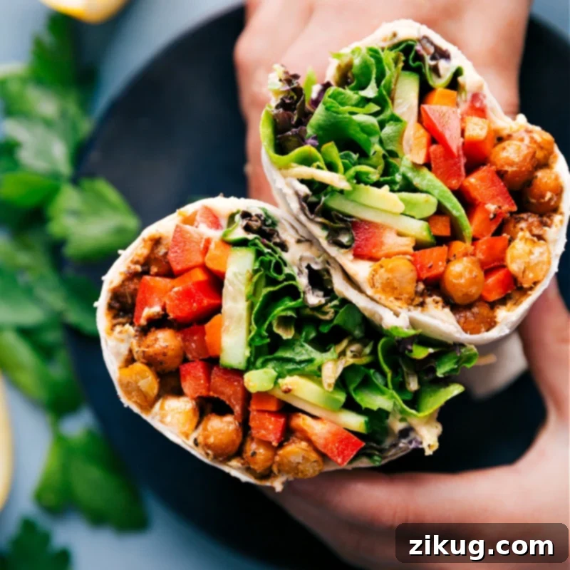 Quick 30-Minute Hummus Wrap A delicious hummus wrap cut in half, revealing crispy chickpeas, fresh vegetables, and a creamy sauce inside.