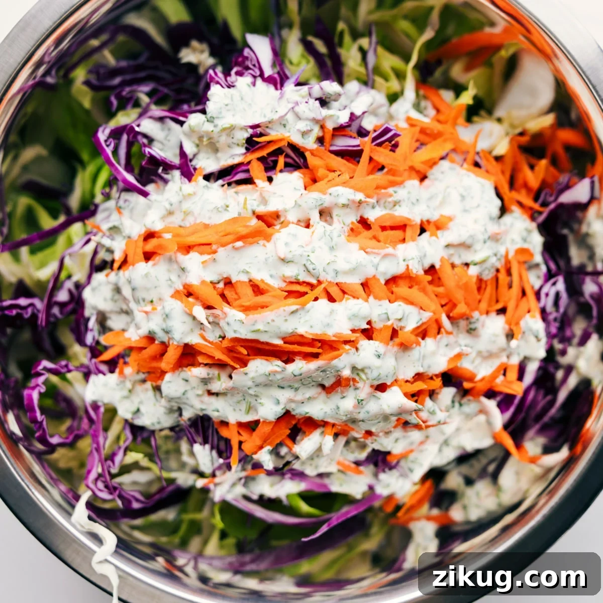 Mexican Slaw Recipe That Everyone Loves All the ingredients added to a large bowl with the dressing drizzled on top.