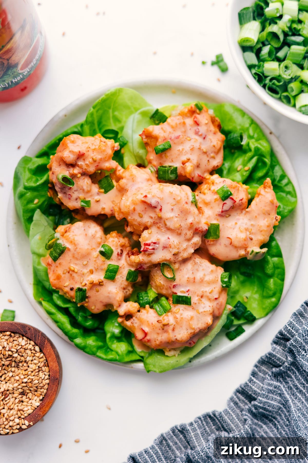 Quick And Easy Bang Bang Shrimp Bang Bang Shrimp served on a bed of lettuce and topped with sliced green onions.