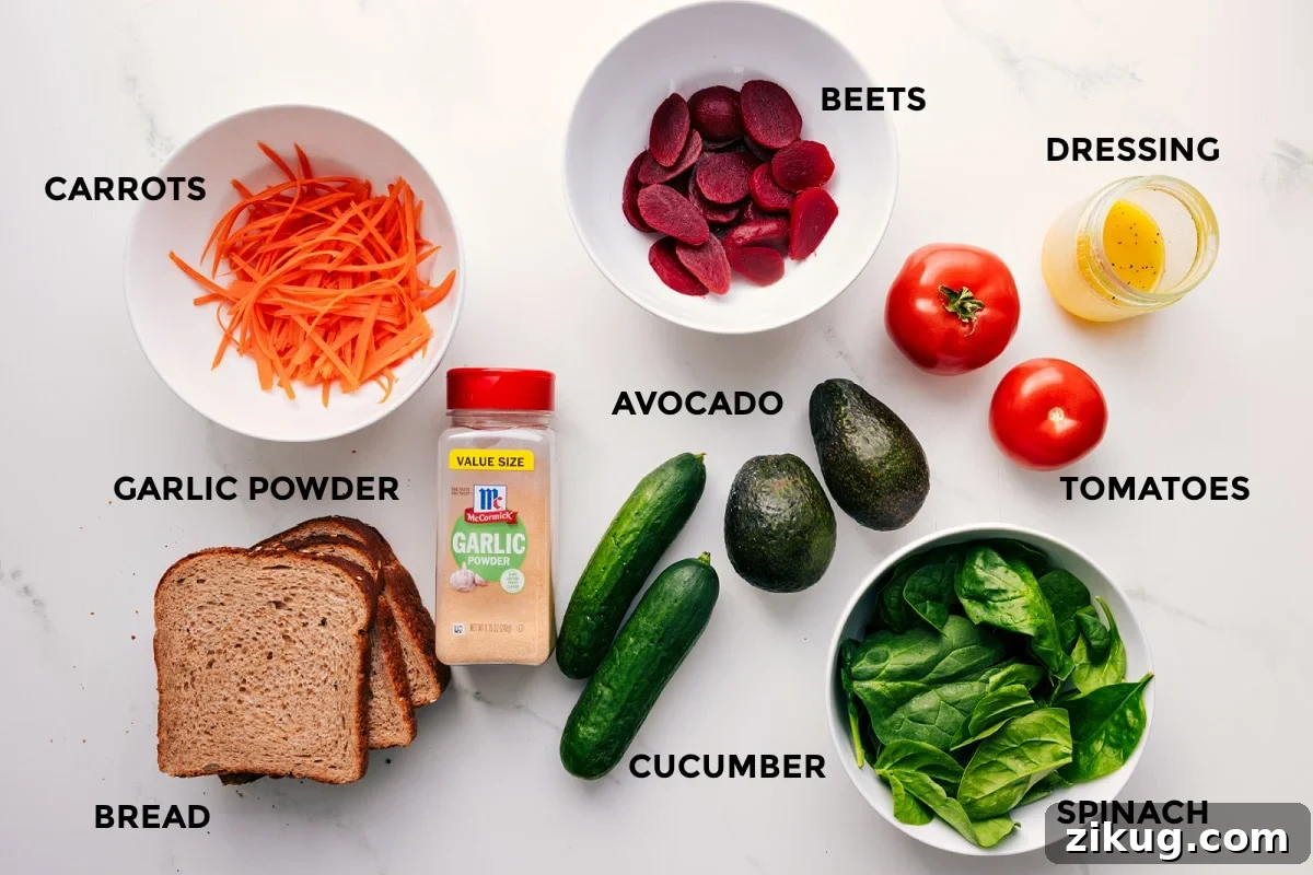Ingredients In This Veggie Sandwich All the ingredients in this recipe prepped out for easy assembly including the carrots, garlic powder, bread, beets, avocado, cucumber, spinach, tomatoes, and dressing.