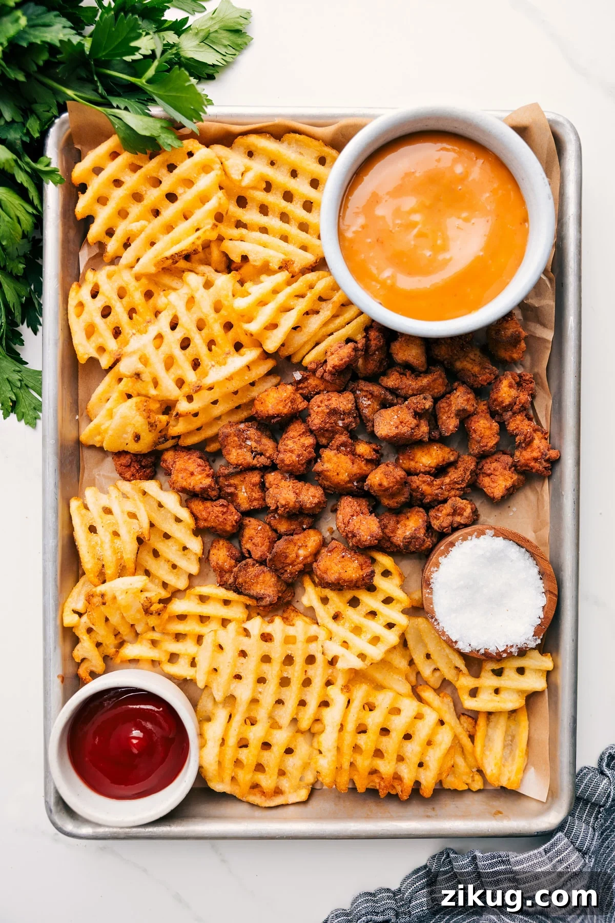Chick-Fil-A Nuggets Recipe With Chick-Fil-A Sauce Chick-fil-A Nuggets Recipe served on a sheet pan with fries and dipping sauce on the side.