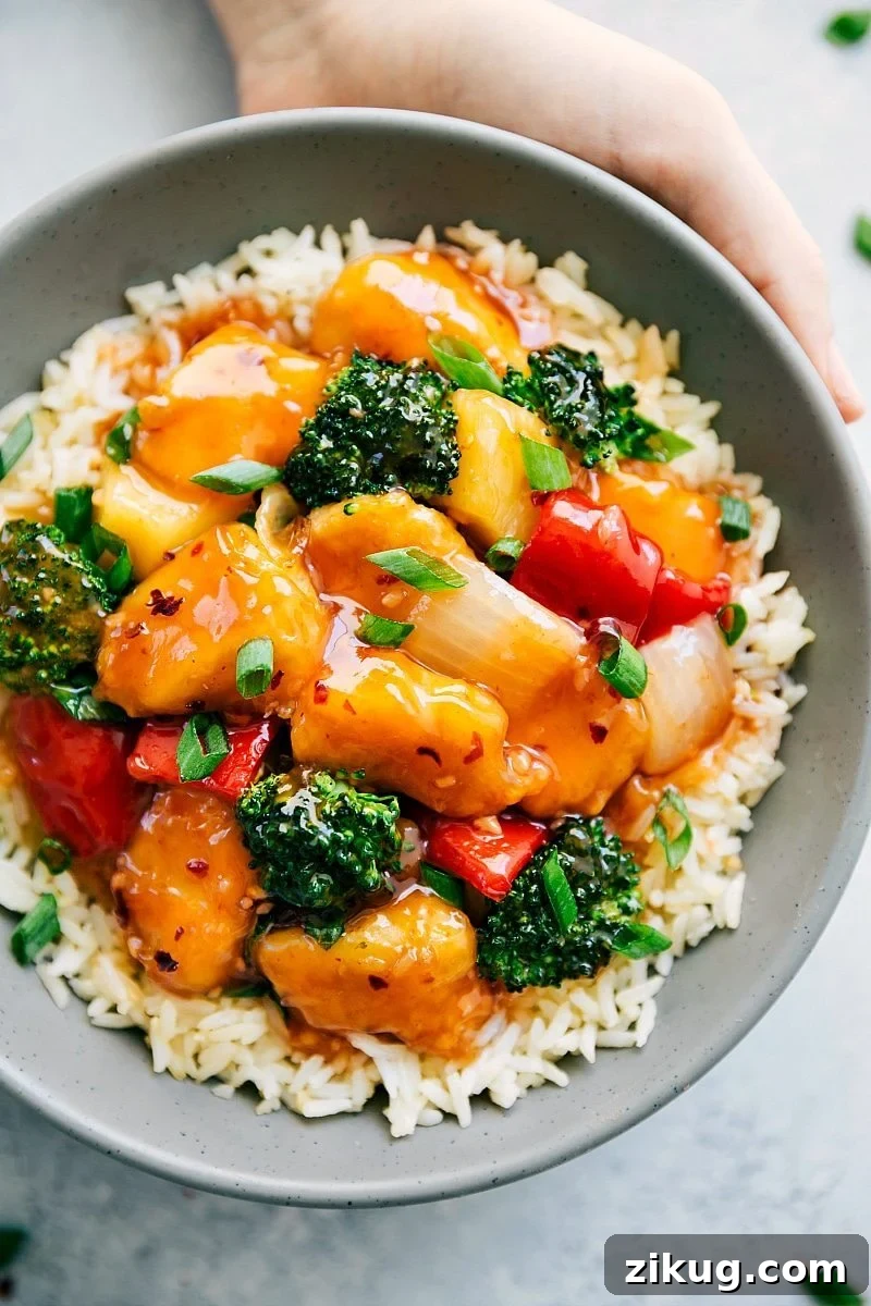 Sweet And Sour Chicken Baked sweet and sour chicken on a bed of rice with fresh green onions on top.