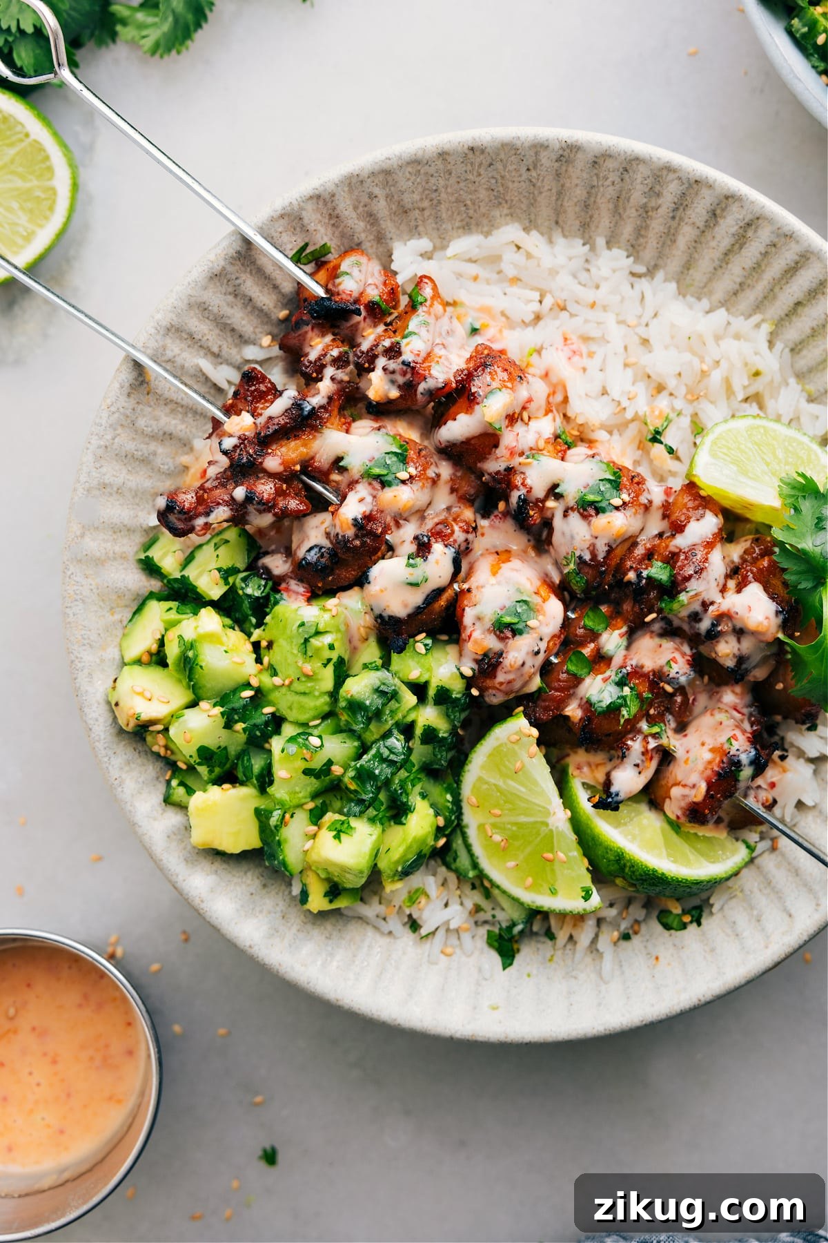 Bang Bang Chicken Skewers Bang bang chicken skewers with rice and a cucumber salad.