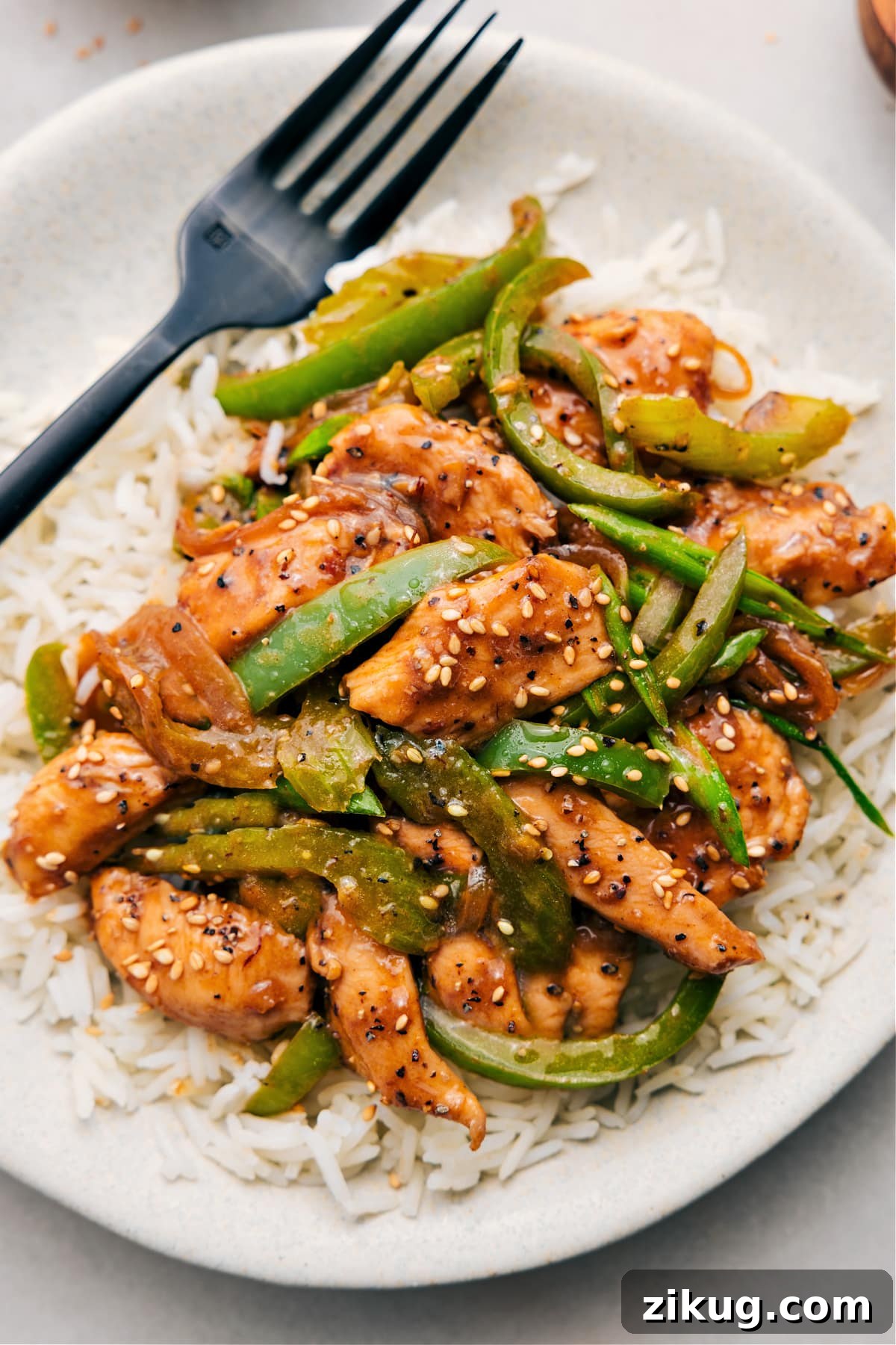 Black Pepper Chicken Asian Chicken Recipes: Black pepper chicken served over rice and topped with sesame seeds.