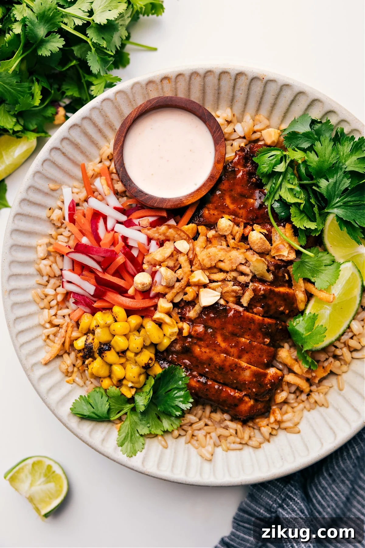 Asian Chicken Recipes Asian Chicken Bowl with sauce on the side and fresh herbs on top.