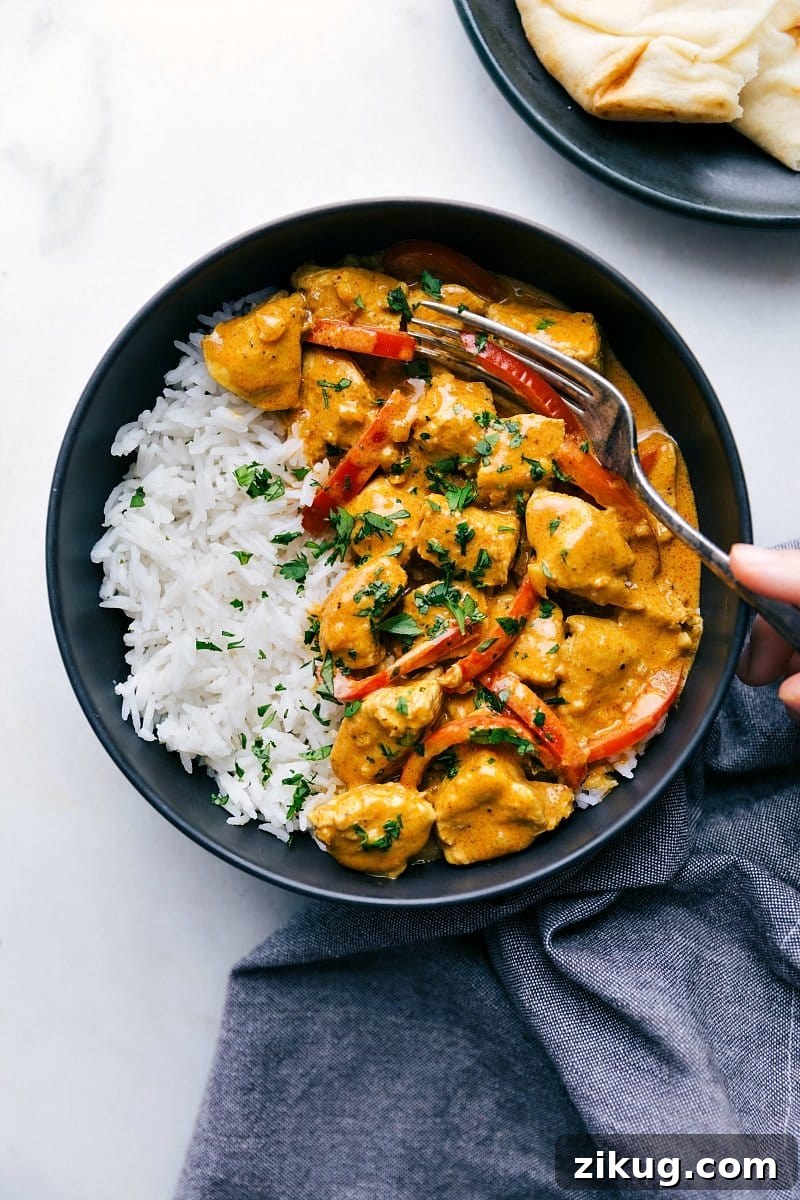 Coconut Chicken Curry Ready-to-eat coconut curry chicken, creamy and flavorful, with a fork in it, served alongside fluffy rice and warm naan bread.