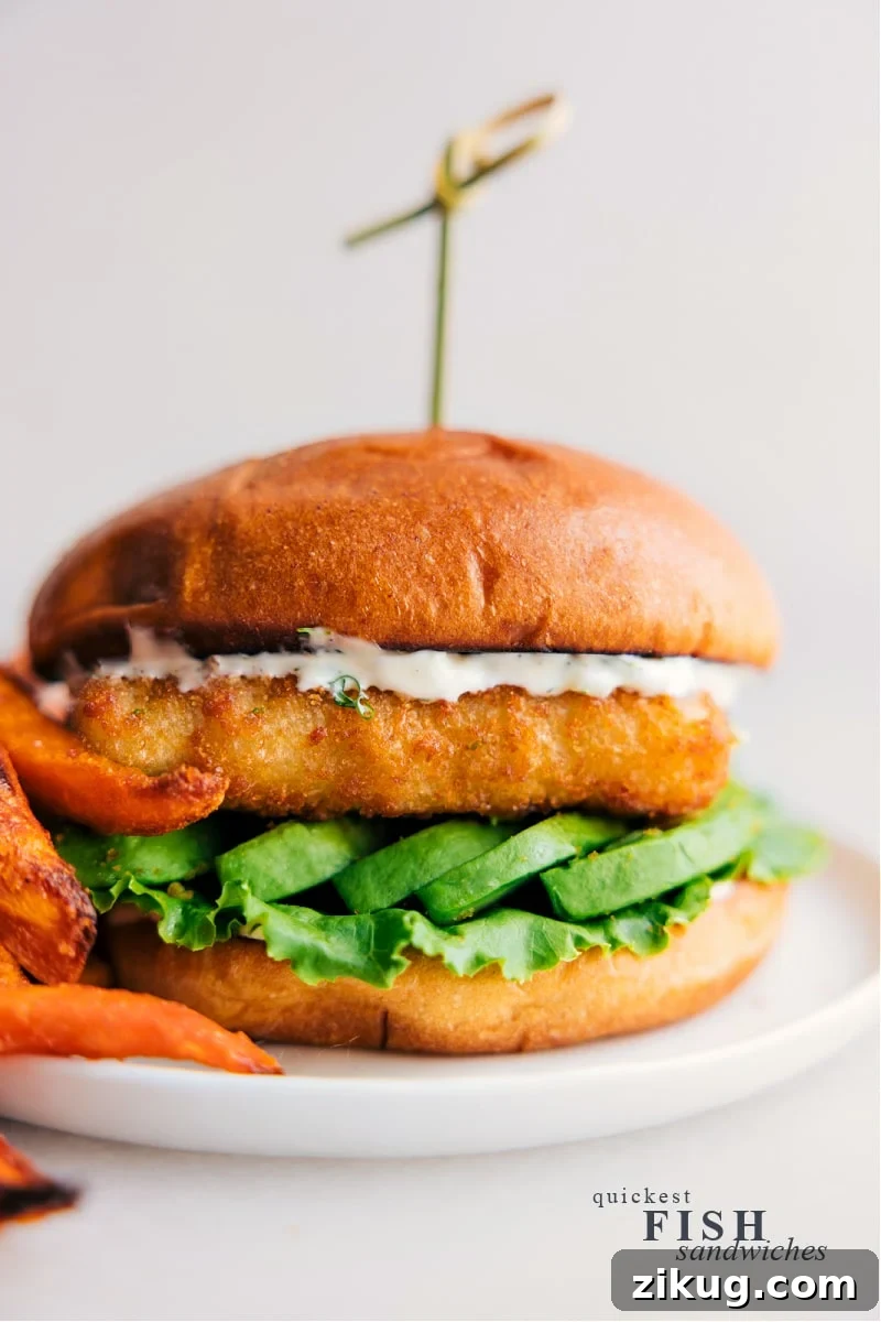This Fish Sandwich layers a flaky fish fillet with the rich creaminess of avocado and the tang of a lemon-infused sauce, all sandwiched between buttery toasted brioche buns. It's a flavor-packed bite every time, and ready in under 20 minutes! View of the quickest Fish Sandwich, complete with bun and toppings.