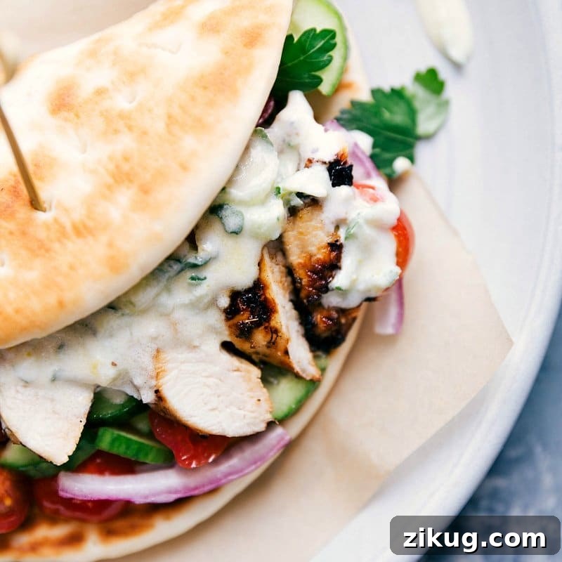 Greek Chicken Gyro Recipe A complete chicken gyro, overflowing with chicken, vegetables, and sauce, wrapped in a soft pita, ready to be enjoyed as part of a chicken gyro recipe.