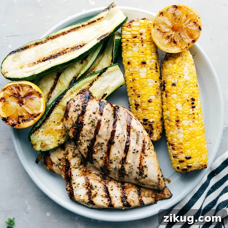 Greek Chicken Recipe The result of perfectly marinated and grilled meat, served with grilled zucchini, corn, and lemons on the side, creating a mouthwatering meal.