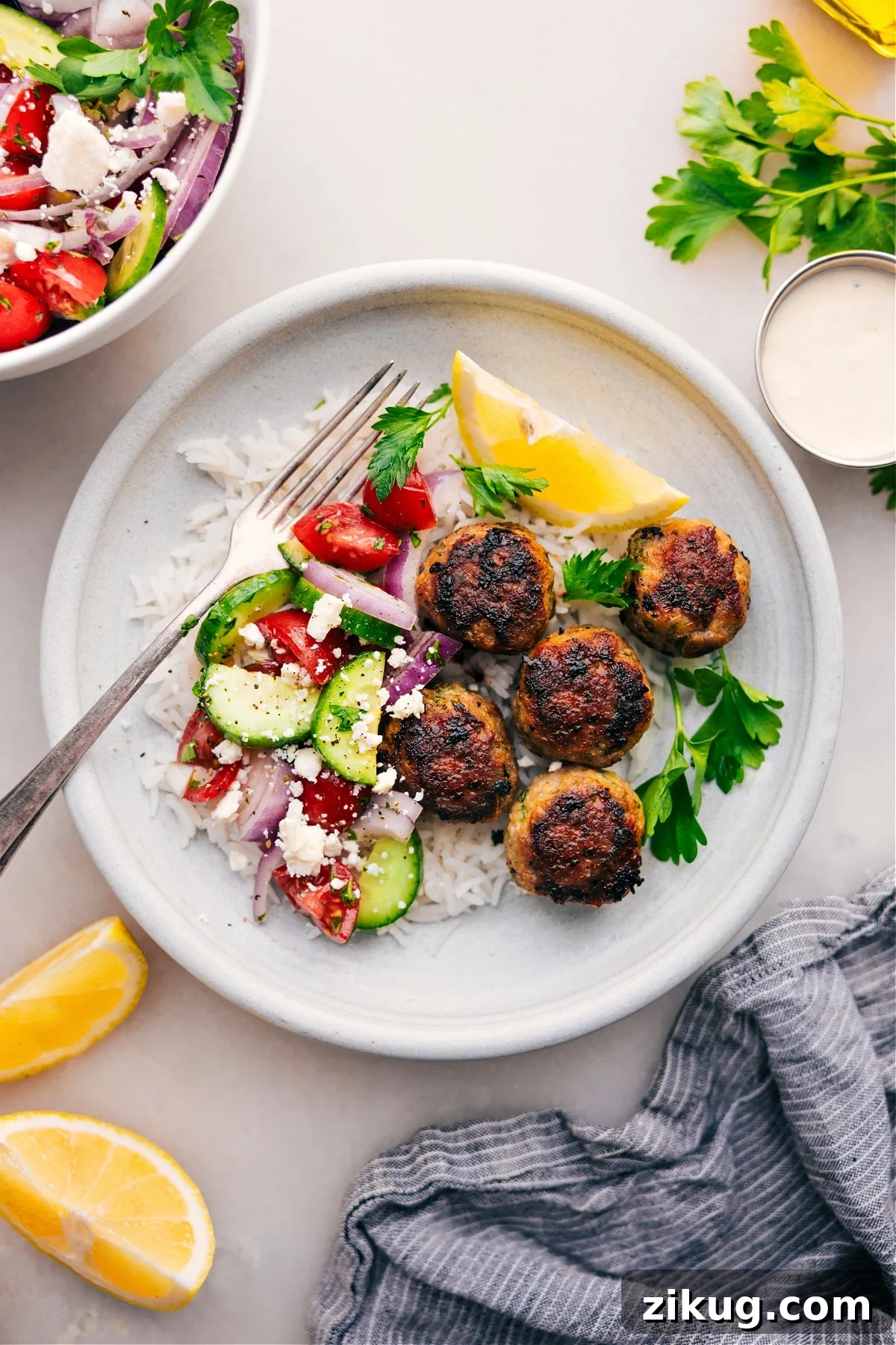 Greek Turkey Meatballs Greek turkey meatballs over rice with a cucumber tomato salad on the side.
