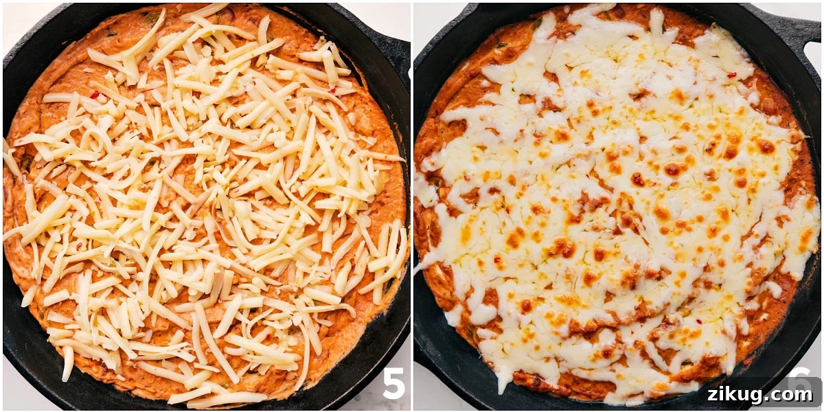 Cheesy And Flavorful Refried Bean Dip Cheese being spread over the appetizer and it all being baked to perfection.
