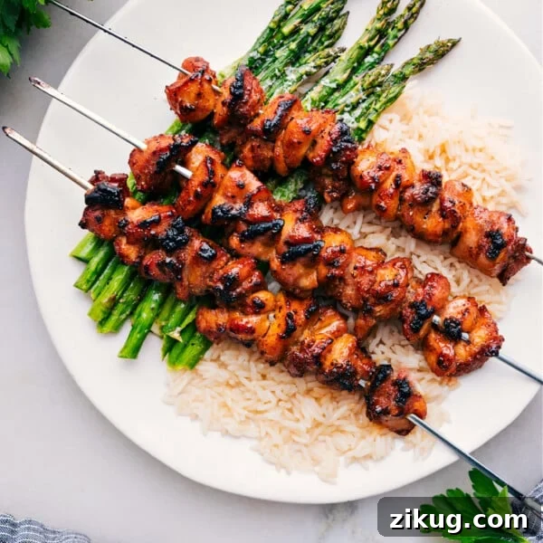 Baked Chicken Bites on skewers over rice and asparagus.