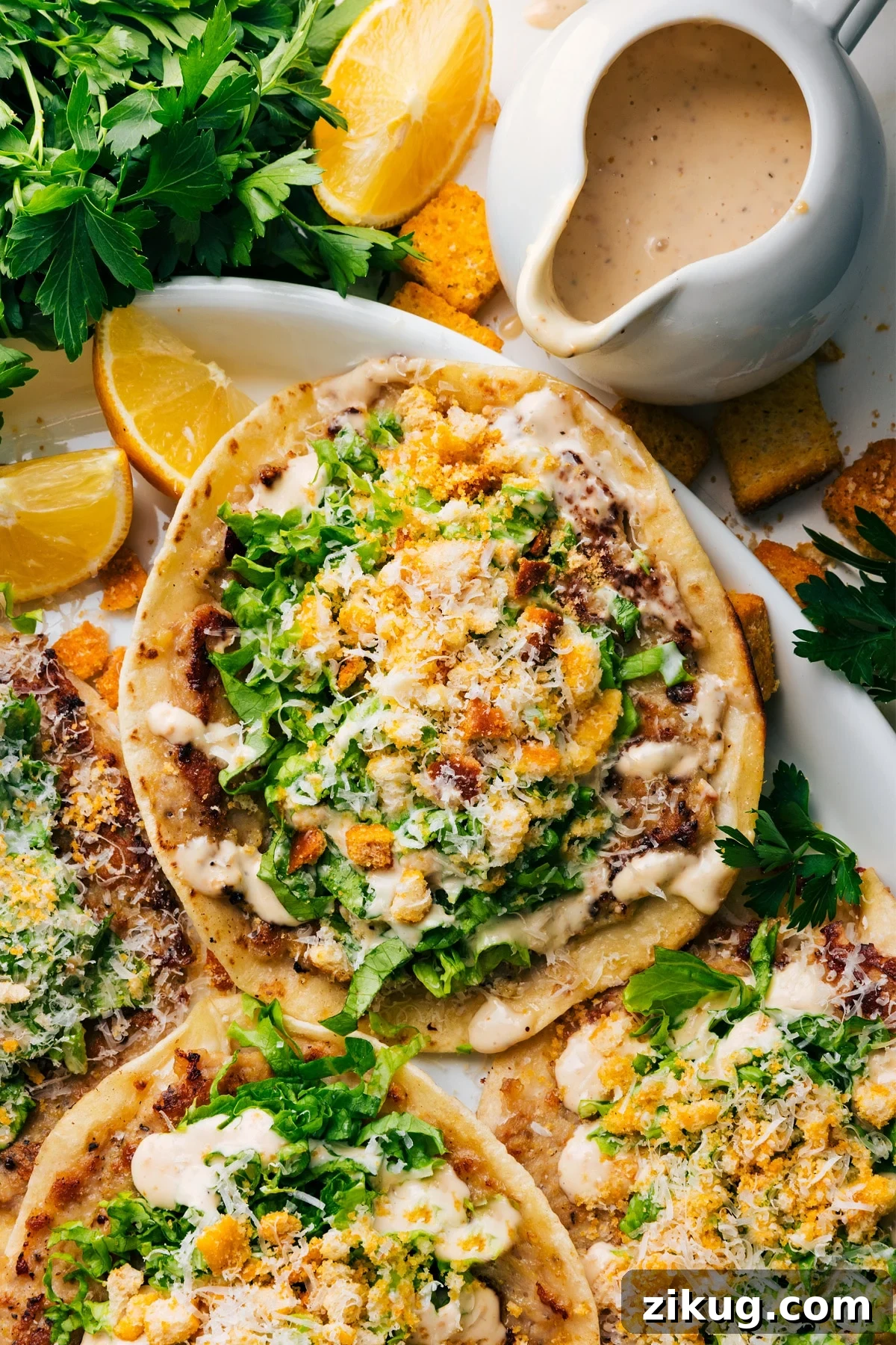 Chicken Caesar Smashed Tacos with Creamy Dressing 2 Chicken Caesar Smashed Tacos on a plate with fresh lemon wedges, extra Caesar dressing, and croutons on the side.