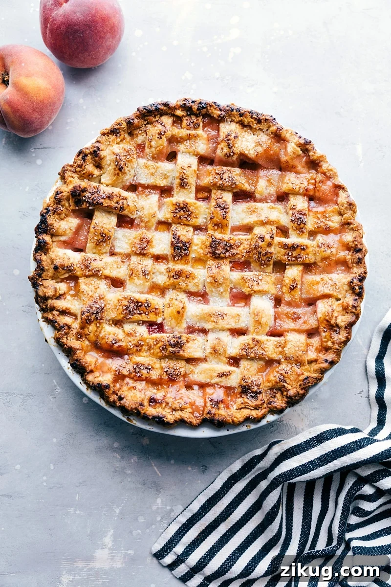 Freshly Baked Peach Pie with Sugar Topping - Accompanied by Fresh Peaches Delicious and sweet peach pie, fresh out of the oven and topped with sugar, accompanied by fresh peaches on the side.