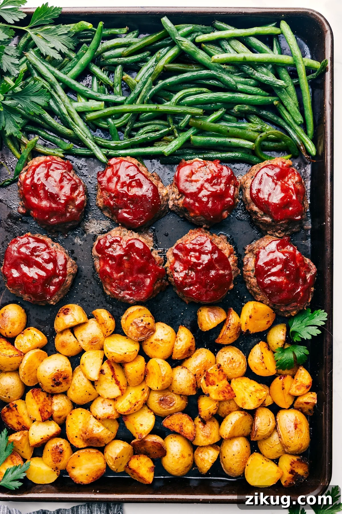 Cajun Chicken In The Crockpot Mini meatloaves with roasted potatoes and tender green beans on a sheet pan.